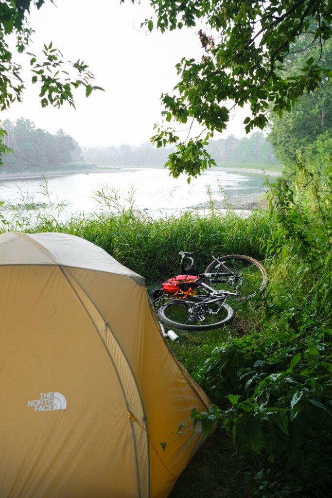 Campement bivouac lors d'un séjour de bikepacking gravel, tente au bord de la rivière