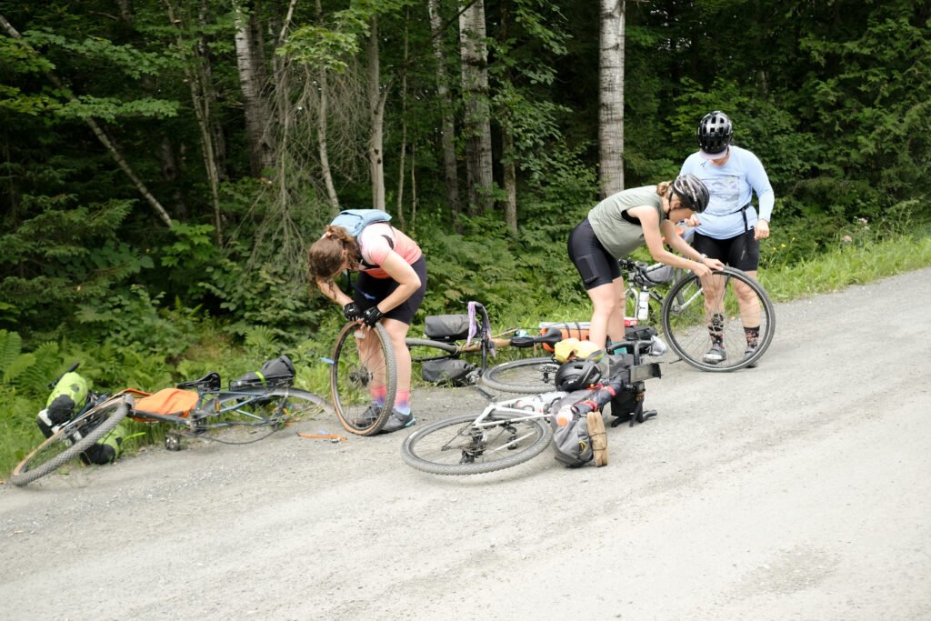 Membres du collectif cycliste Les Fines Garnottes s'entraidant après une crevaison sur un chemin de gravel